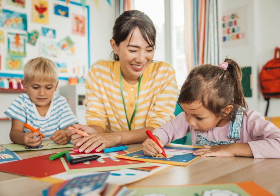 Teacher guiding children in classroom art activity